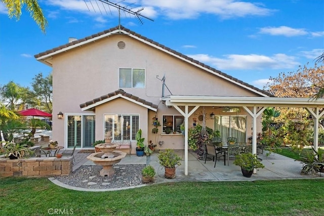 rear view of property featuring a lawn and a patio