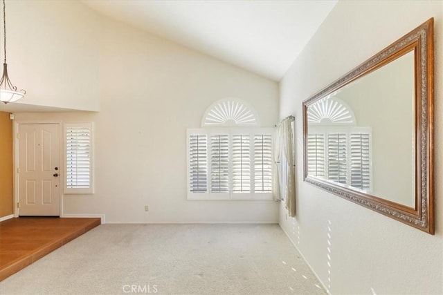 foyer entrance featuring carpet flooring and vaulted ceiling