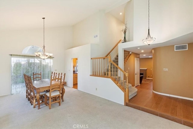 dining room with light hardwood / wood-style flooring, high vaulted ceiling, and a chandelier