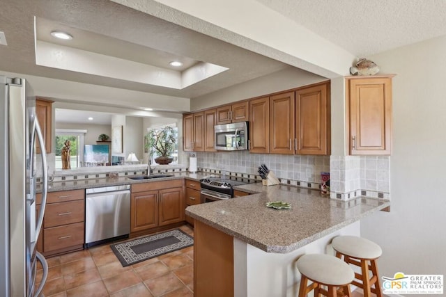 kitchen featuring stone counters, sink, a kitchen bar, kitchen peninsula, and stainless steel appliances