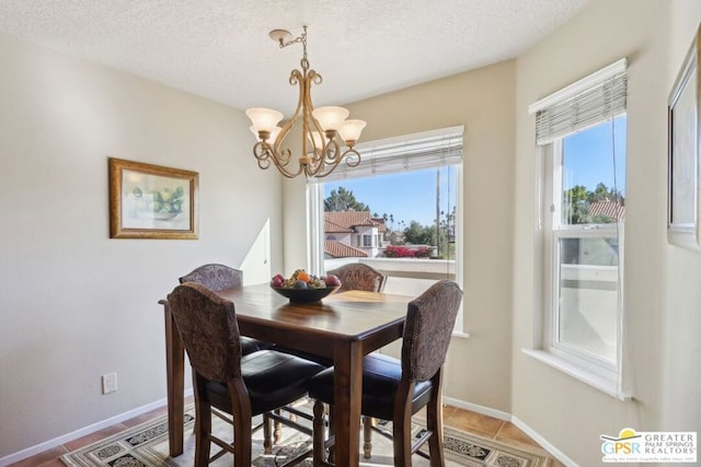 tiled dining space featuring a textured ceiling and a chandelier