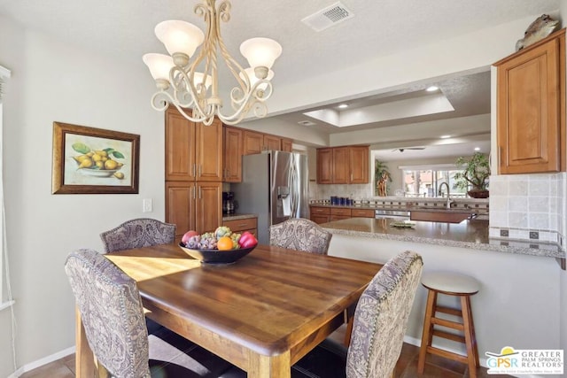 dining room featuring a raised ceiling, sink, and a chandelier