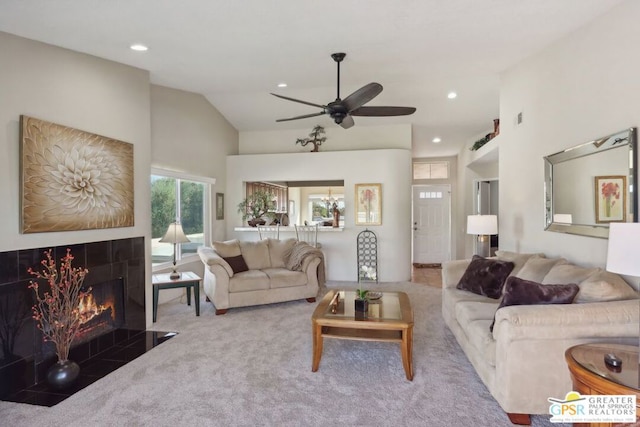 living room featuring carpet, vaulted ceiling, ceiling fan, and a tiled fireplace