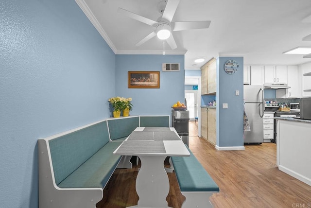 dining area with ceiling fan, crown molding, and light hardwood / wood-style flooring