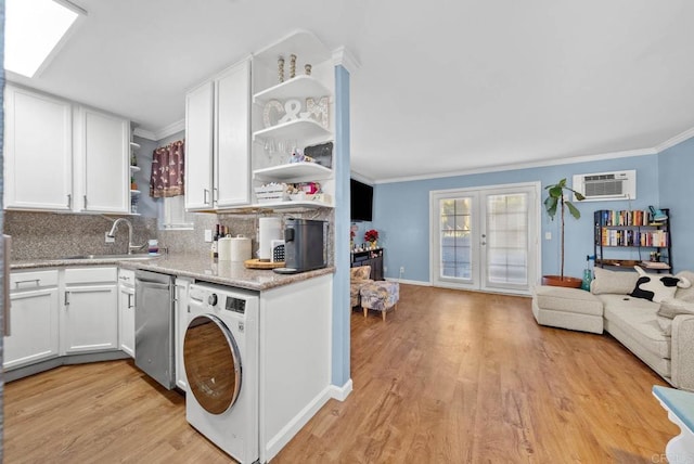 kitchen with white cabinetry, dishwasher, french doors, a wall mounted AC, and washer / dryer