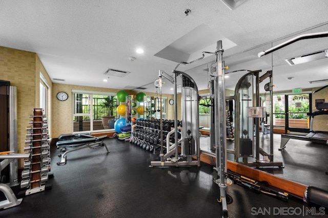 exercise room featuring a healthy amount of sunlight and a textured ceiling