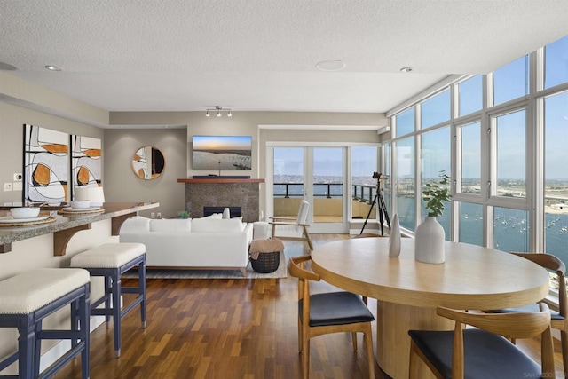 dining area featuring expansive windows, dark wood-type flooring, and a textured ceiling