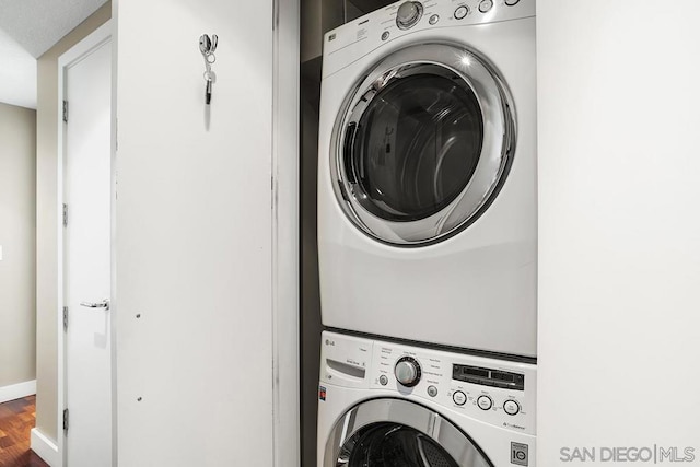 laundry room featuring stacked washer and dryer and hardwood / wood-style flooring