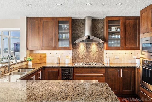 kitchen featuring wine cooler, wall chimney exhaust hood, light stone countertops, and sink