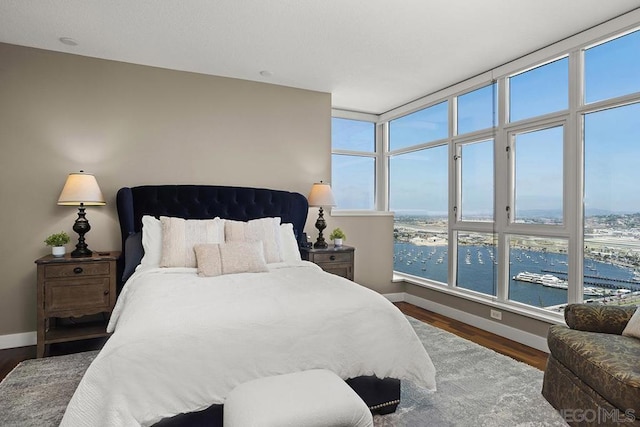 bedroom with a water view and hardwood / wood-style flooring