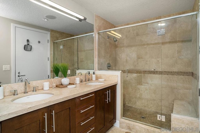 bathroom featuring vanity, an enclosed shower, and a textured ceiling