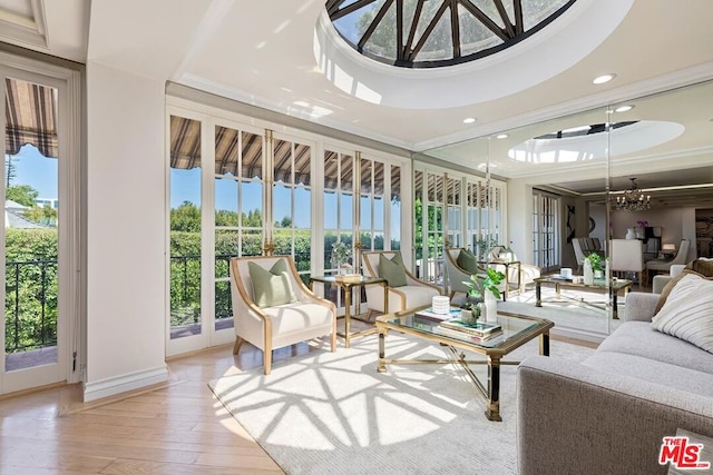 sunroom / solarium featuring a healthy amount of sunlight, a tray ceiling, and a chandelier