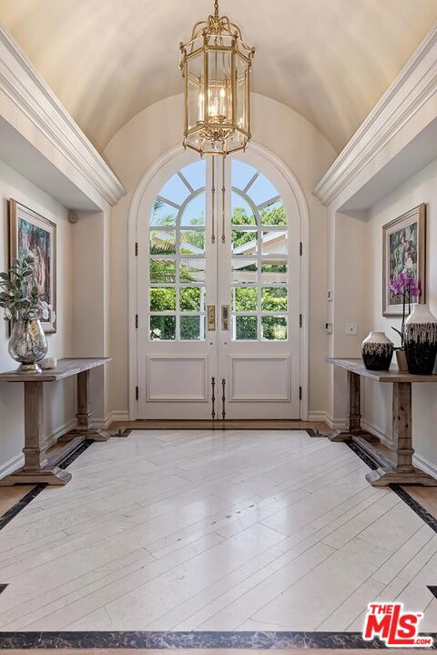 entryway featuring french doors, light hardwood / wood-style flooring, a chandelier, and vaulted ceiling