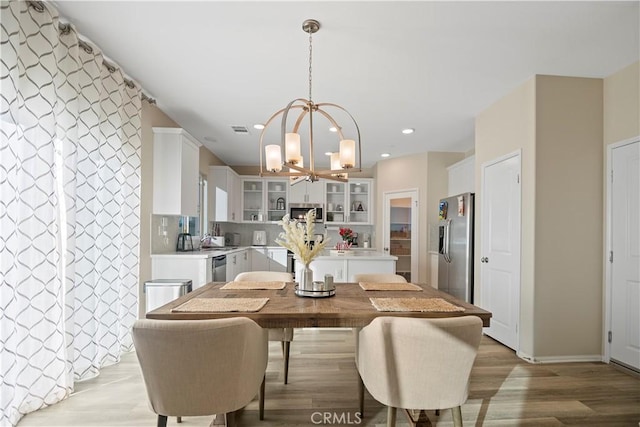 dining space with light hardwood / wood-style floors, sink, and a chandelier