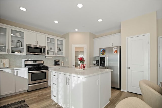 kitchen featuring tasteful backsplash, stainless steel appliances, light hardwood / wood-style flooring, a center island, and white cabinetry