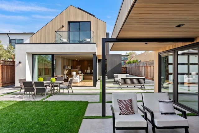 back of property featuring outdoor lounge area, a balcony, a yard, and a patio