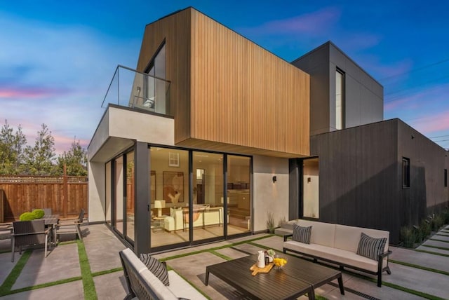 back house at dusk featuring an outdoor living space and a patio