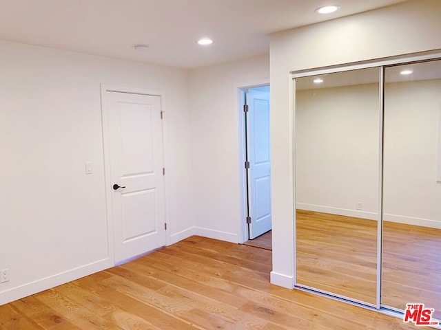 unfurnished bedroom with a closet and light hardwood / wood-style flooring