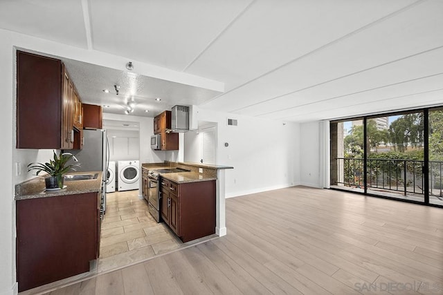 kitchen with washing machine and clothes dryer, sink, light wood-type flooring, appliances with stainless steel finishes, and light stone countertops