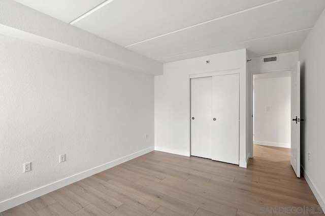 unfurnished bedroom with a closet and light wood-type flooring