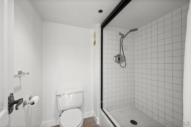 bathroom with a tile shower and toilet