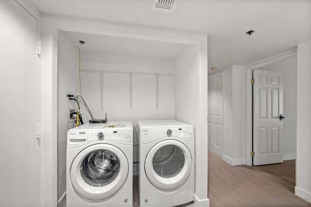 laundry room featuring light hardwood / wood-style flooring and washing machine and clothes dryer