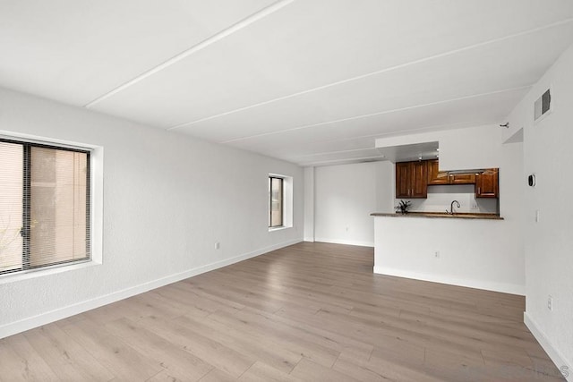 unfurnished living room with sink and light wood-type flooring