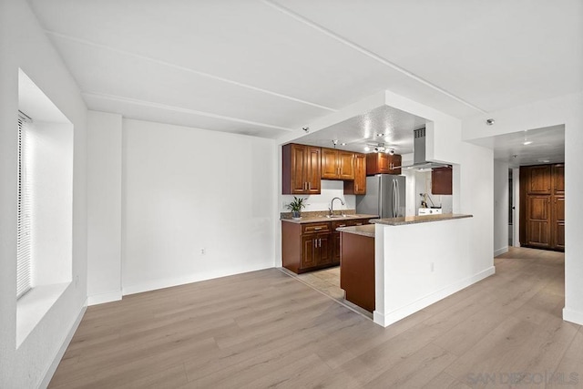 kitchen with island range hood, stainless steel fridge, kitchen peninsula, and light wood-type flooring