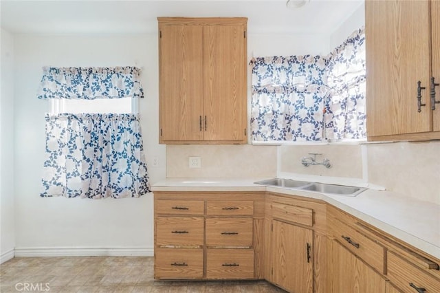 kitchen with tasteful backsplash, light brown cabinetry, and sink