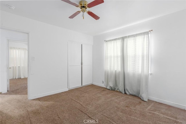 unfurnished bedroom with ceiling fan, a closet, and light carpet