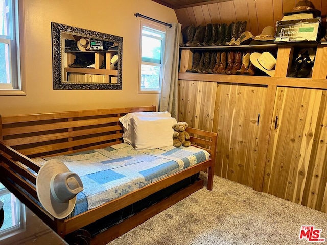 bedroom with carpet floors and wooden walls