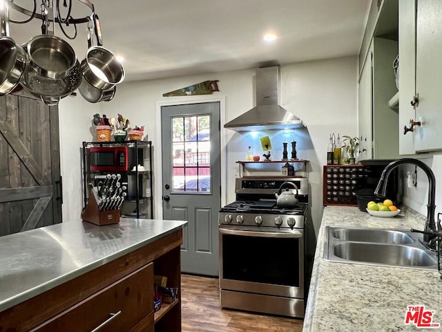 kitchen with wall chimney exhaust hood, stainless steel counters, sink, dark wood-type flooring, and stainless steel range oven