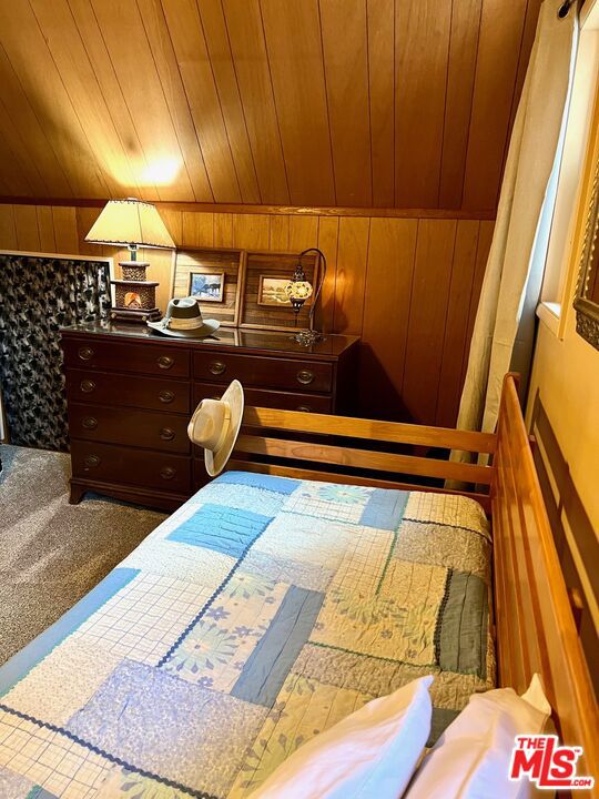 carpeted bedroom featuring wood walls, wood ceiling, and vaulted ceiling