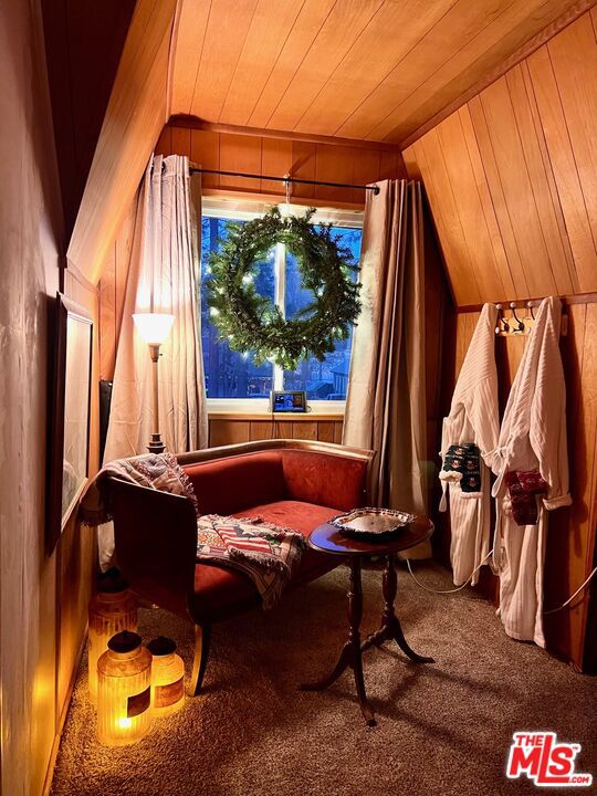 sitting room with wooden walls, carpet floors, lofted ceiling, and wood ceiling