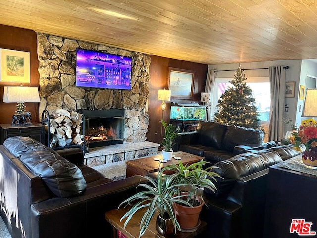 living room with a stone fireplace, wood ceiling, and wooden walls