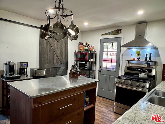 kitchen featuring gas range, a center island, wall chimney range hood, a barn door, and dark hardwood / wood-style floors