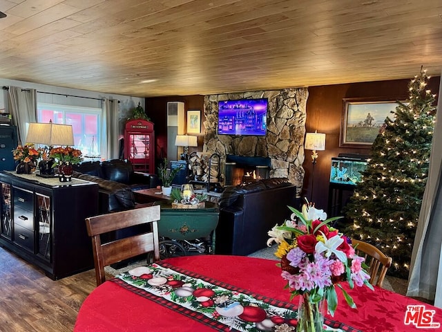 interior space with dark hardwood / wood-style flooring, a stone fireplace, and wooden ceiling