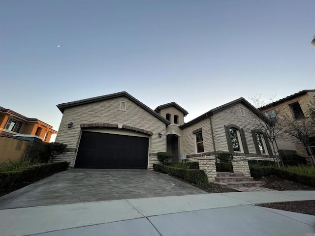 view of front of home featuring stone siding, concrete driveway, and an attached garage