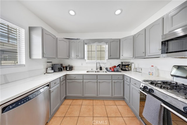 kitchen with gray cabinets, sink, light tile patterned floors, and stainless steel appliances