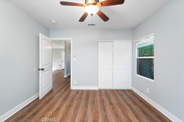 unfurnished bedroom with ceiling fan, dark wood-type flooring, and a closet