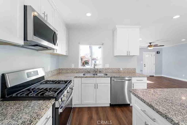 kitchen featuring light stone countertops, white cabinets, appliances with stainless steel finishes, sink, and ceiling fan