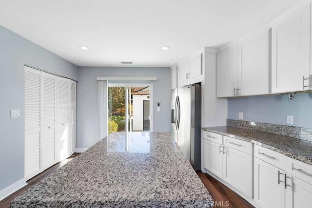 kitchen featuring stainless steel fridge with ice dispenser, white cabinetry, dark wood-type flooring, stone countertops, and a center island