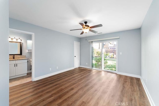 unfurnished bedroom with ceiling fan, sink, wood-type flooring, and ensuite bath