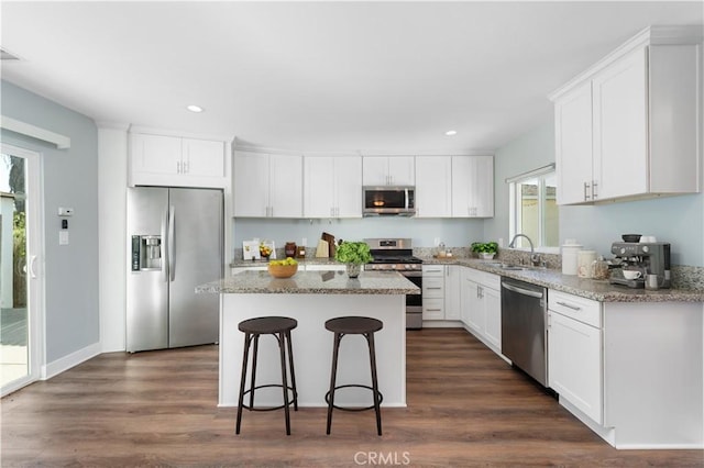 kitchen with stainless steel appliances, white cabinetry, a kitchen island, and sink