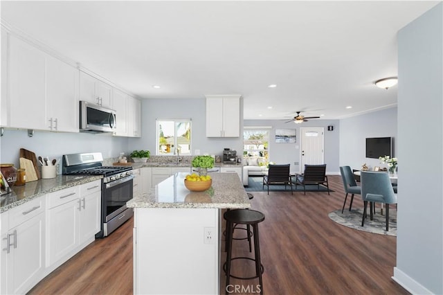 kitchen with a kitchen island, dark wood-type flooring, white cabinetry, stainless steel appliances, and ceiling fan