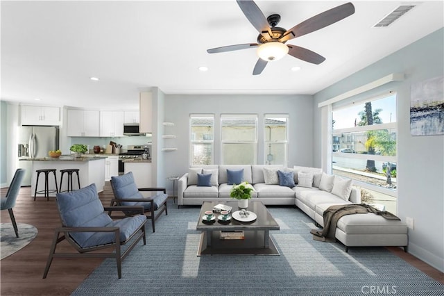 living room featuring dark wood-type flooring and ceiling fan