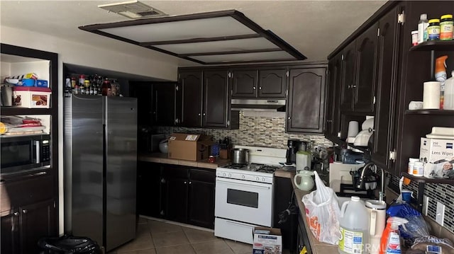 kitchen featuring tile patterned flooring, decorative backsplash, white gas range, tile counters, and stainless steel refrigerator