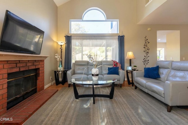 living room featuring a brick fireplace, hardwood / wood-style flooring, and a towering ceiling