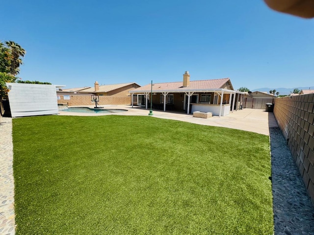 rear view of property with a patio area, a fenced in pool, and a yard