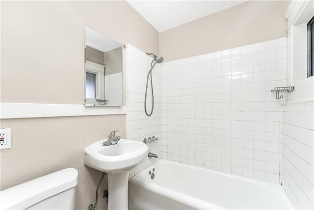 bathroom featuring tiled shower / bath combo and toilet